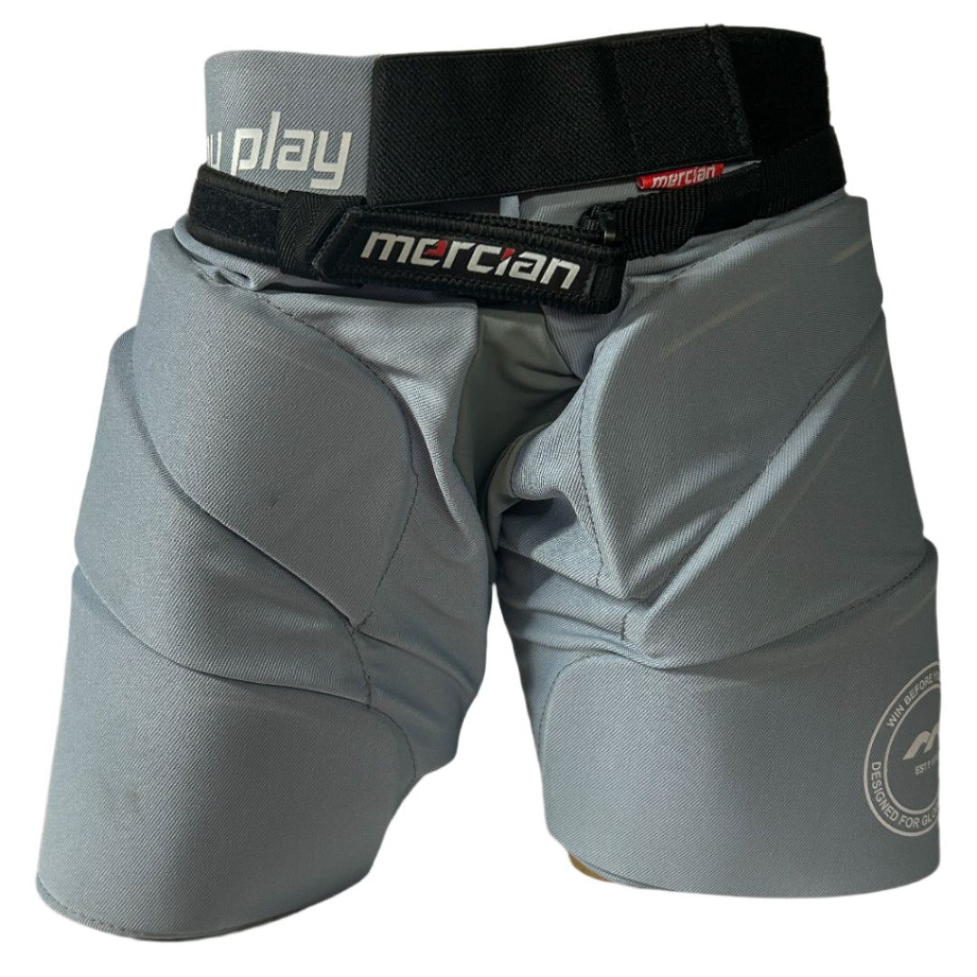 Gray hockey pants with a black belt featuring 'mercian' branding on a beige background.