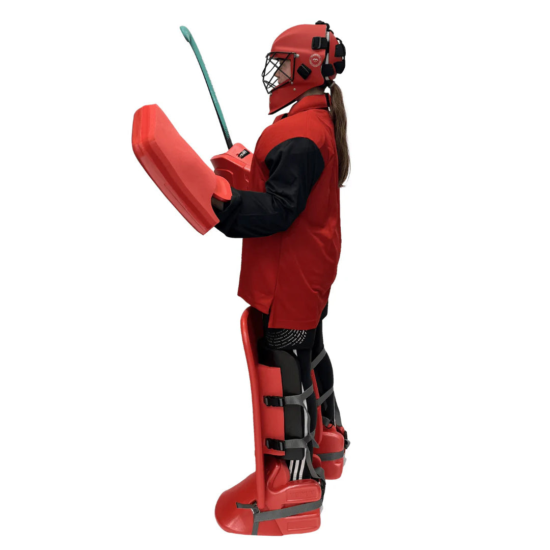 Person wearing a full red protective field hockey set with helmet and boots on a white background