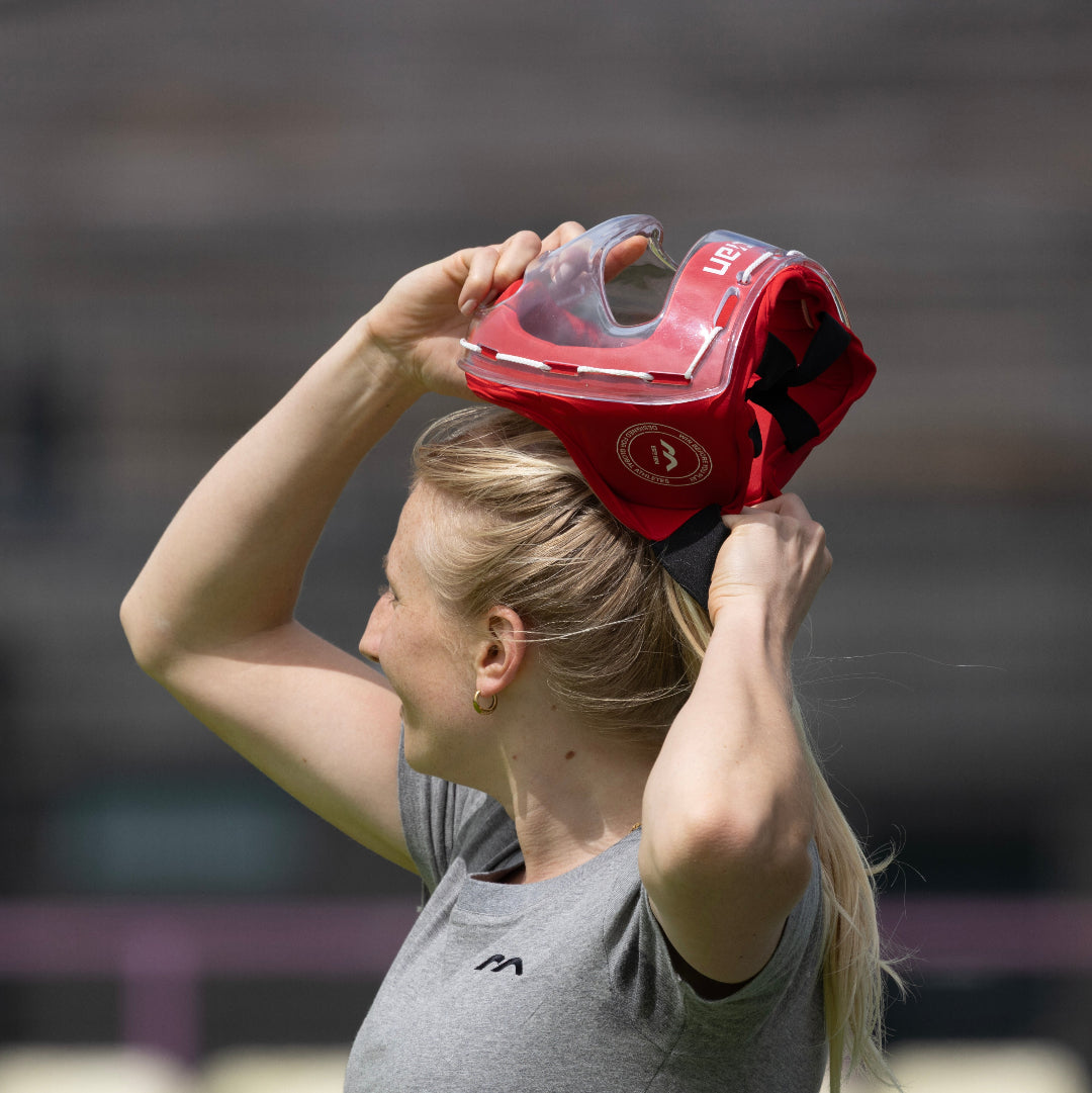 Field Hockey player wearing a red face mask