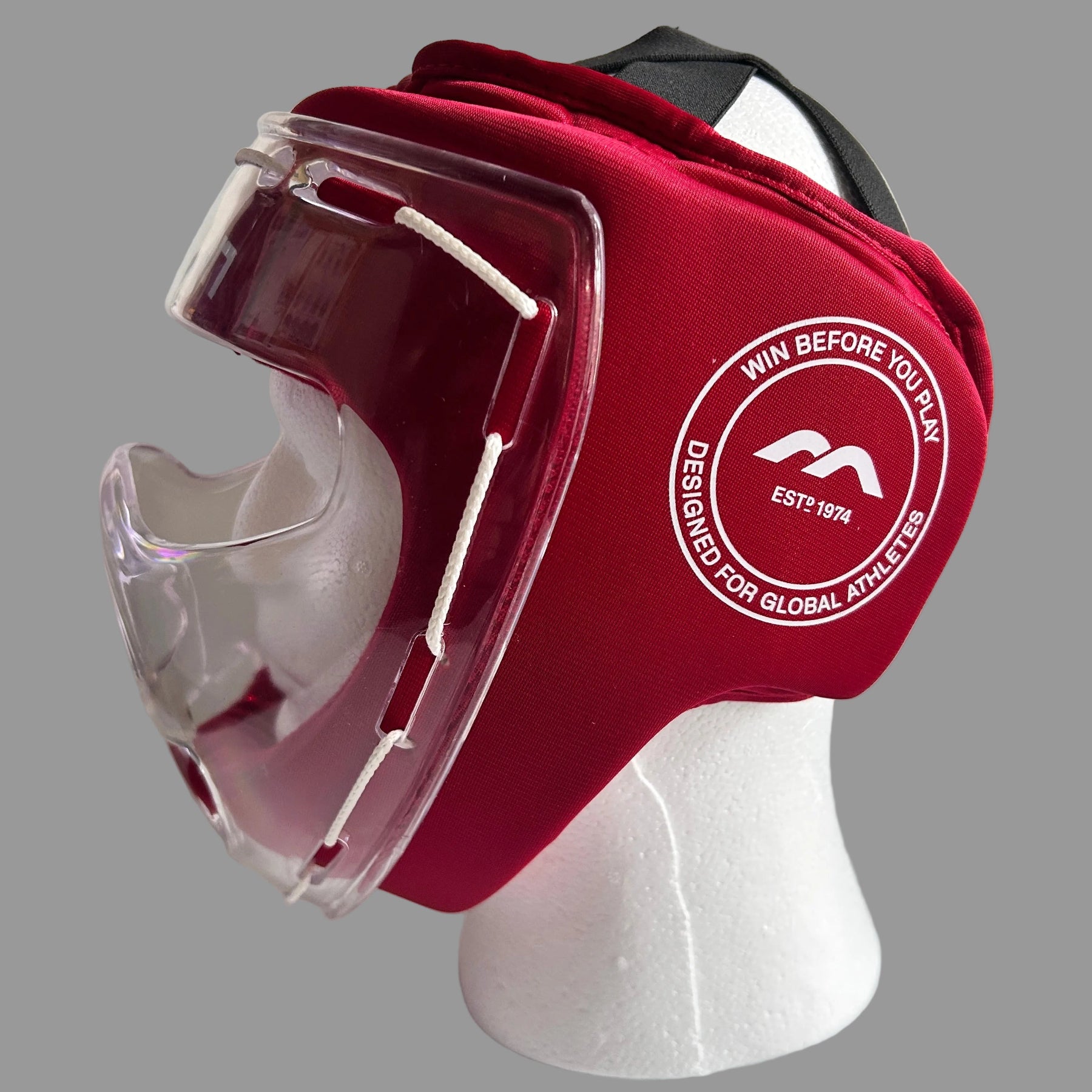 A red field hockey protective headgear with an integrated clear face guard, displayed on a white styrofoam mannequin head against a white background.