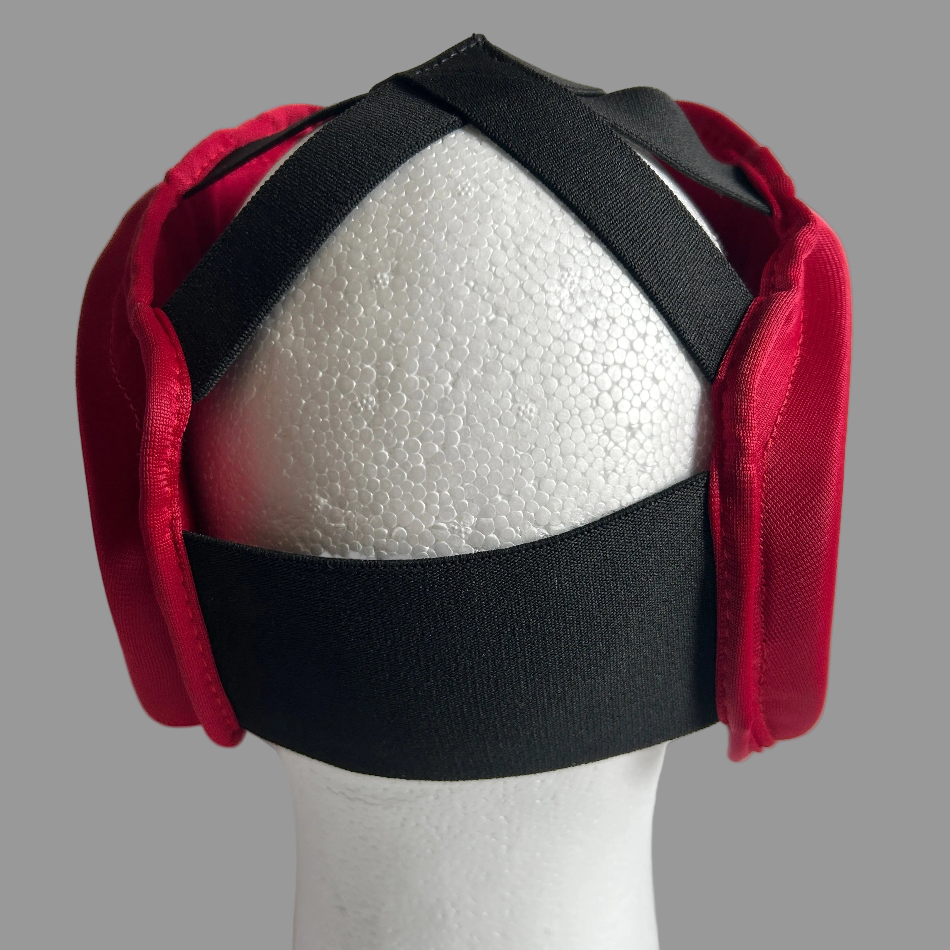 Red and black padded headband or head harness displayed on a white styrofoam mannequin head against a white background.