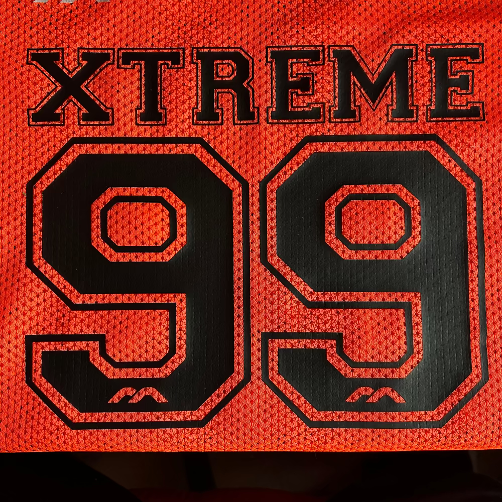 Orange mesh field hockey jersey with Xtreme 99 text